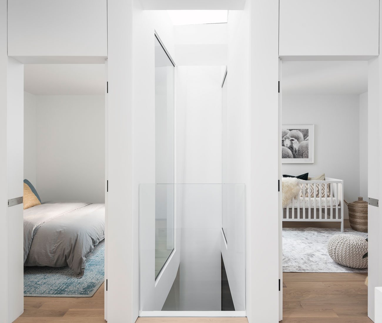 Top-floor landing with two sunlit bedrooms illuminated by an adjacent light well, featuring beds, area rugs, and a pouf from Ikea.