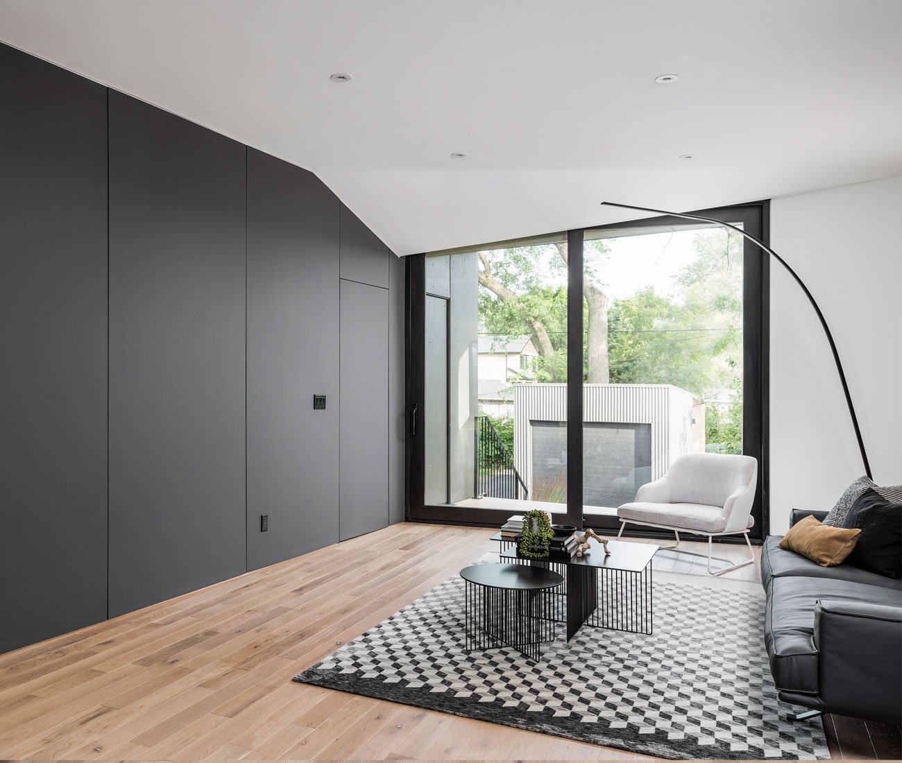 Living room with angled drywall mimicking faceted exterior, ceiling pocket concealing sliding door track. Phaedrus Studio Tesseract House