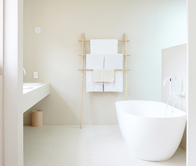 A freestanding white bathtub perfectly positioned to face a modern hanging sink, creating a sleek and minimalist bathroom vibe.