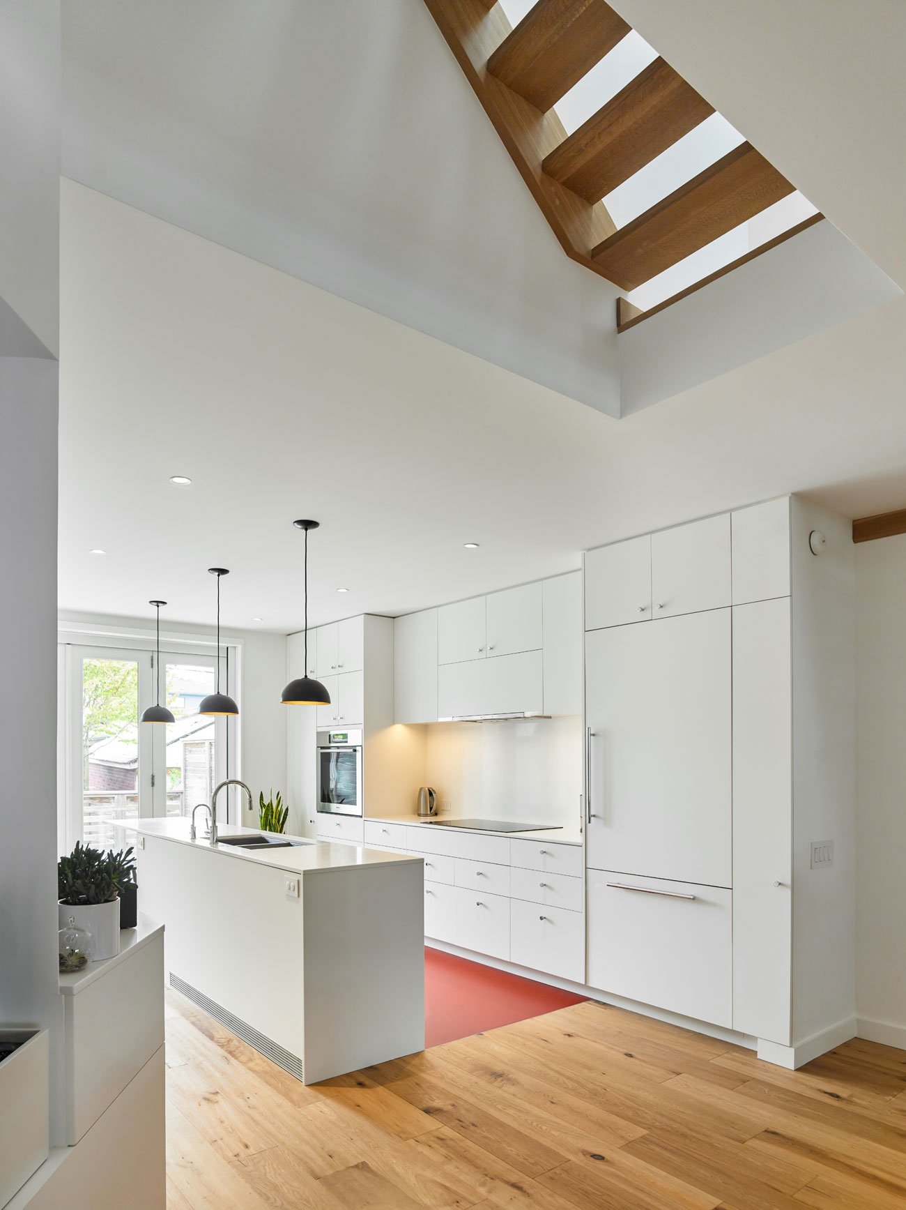 White kitchen with an island on a Leslieville semi by Brian O’Brian Architect