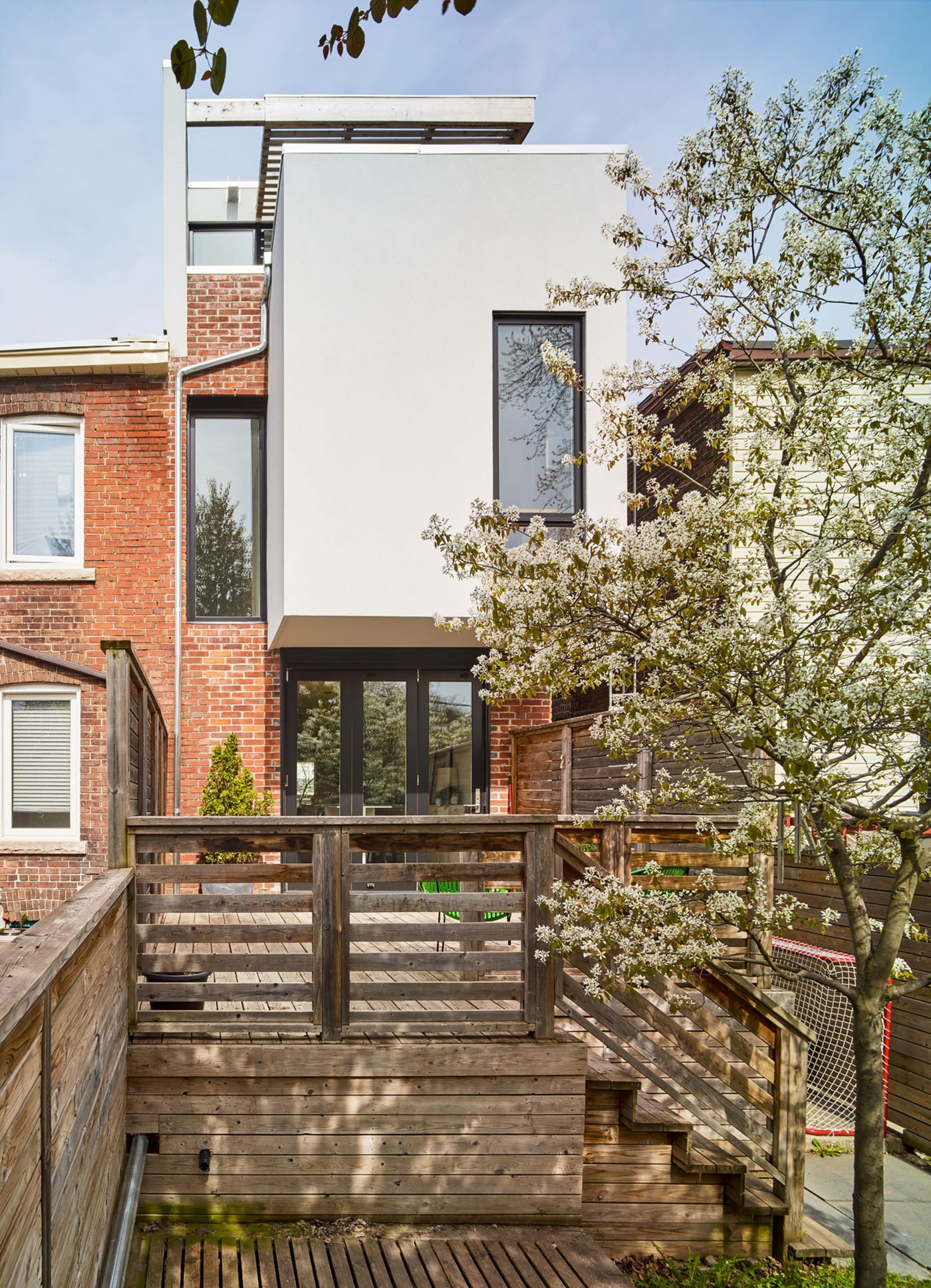 View of a Leslieville semi backyard with second-storey addition cantilevers and cedar pergola–covered green roof. Brian O’Brian Architect